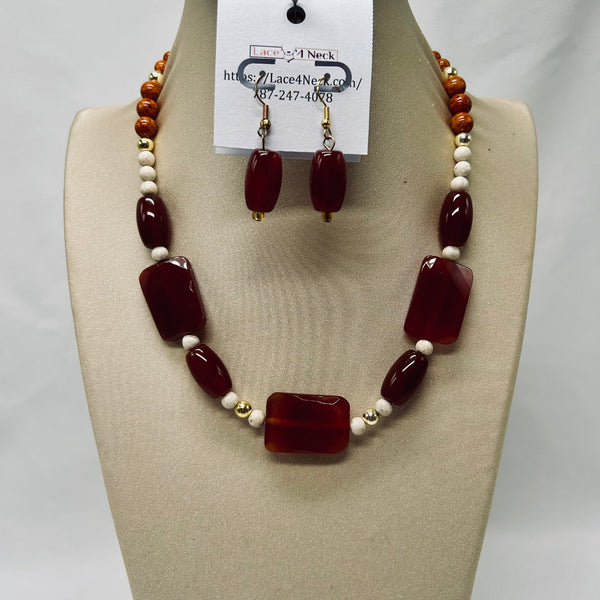 Jewelry set with necklace and earrings on a mannequin bust, featuring red and white beads.