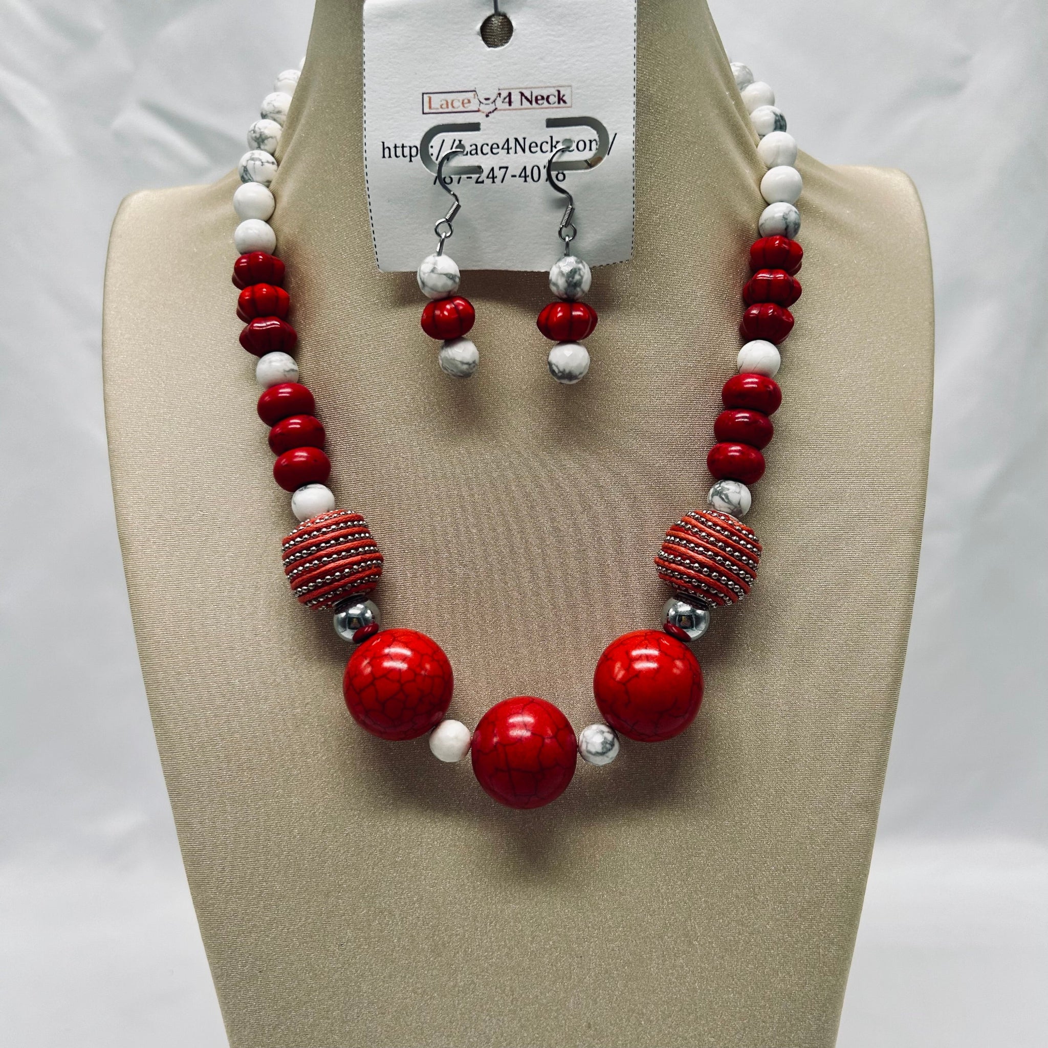Necklace and earrings set with red, white, and silver beads on a mannequin bust.