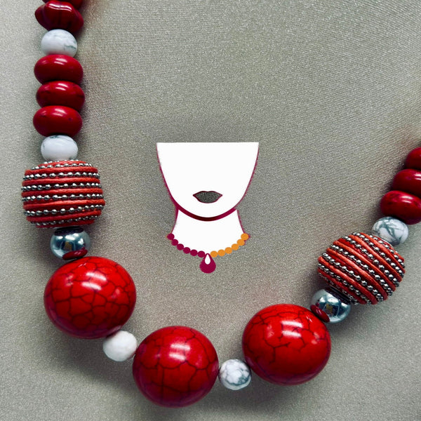 Necklace with red, white, and silver beads on a gray background