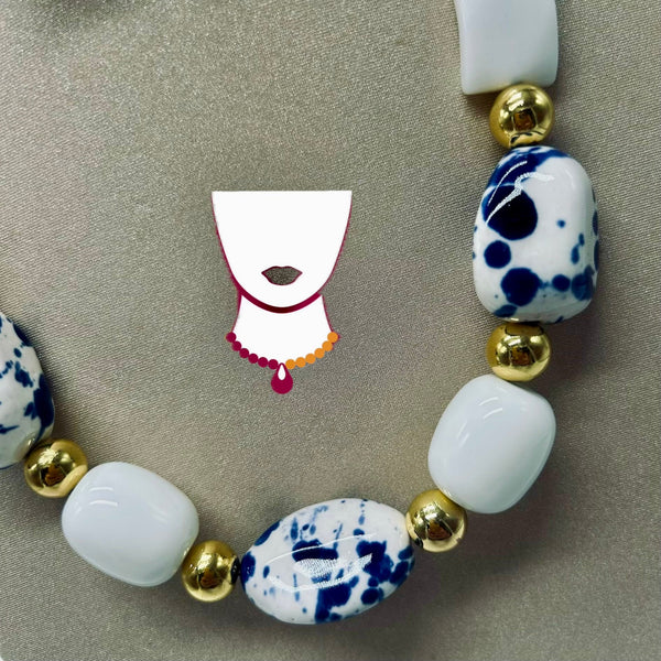 Necklace with white, blue, and gold beads on a beige background