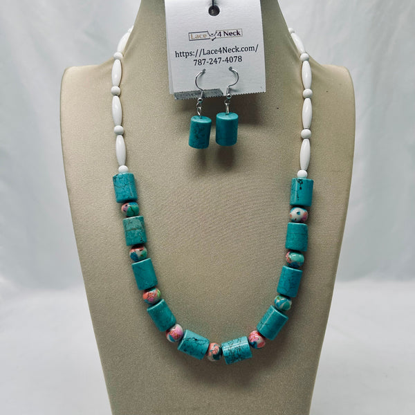 Turquoise and white beaded necklace with matching drop earrings displayed on a beige jewelry bust. The necklace features textured turquoise cylindrical beads, white round beads, and small pink-and-white marbled accent beads.