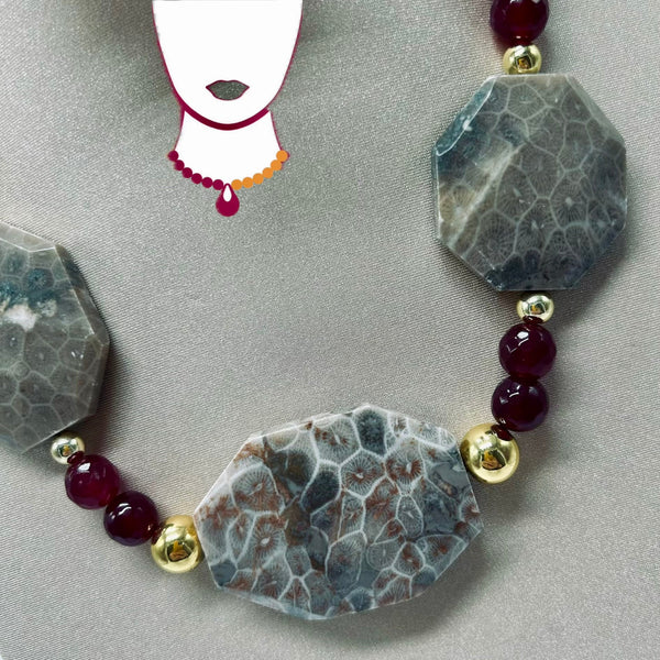 Necklace with gray stone and red bead details on a gray background