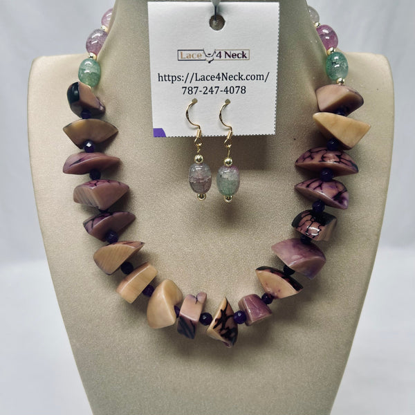 A beaded necklace and matching drop earrings displayed on a beige jewelry bust. The necklace features irregular polished beads in purple, cream, and black marbled patterns, with small dark purple spacer beads.