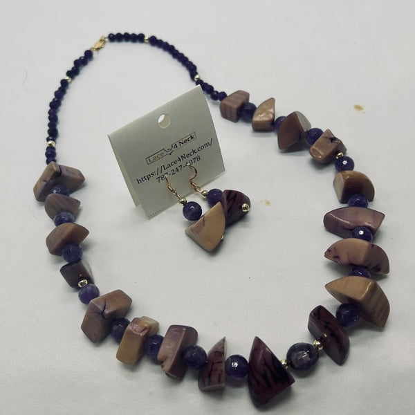 A beaded necklace and matching drop earrings displayed on a white background. The necklace features irregular polished stone beads in earthy brown and beige tones, dark purple faceted beads, and small gold spacer rings.