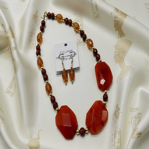 Necklace and earrings set with red and brown beads on a white background