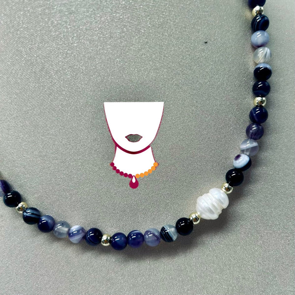 Beaded necklace with blue, black, and white beads on a gray background with a small illustration of a bonnet.
