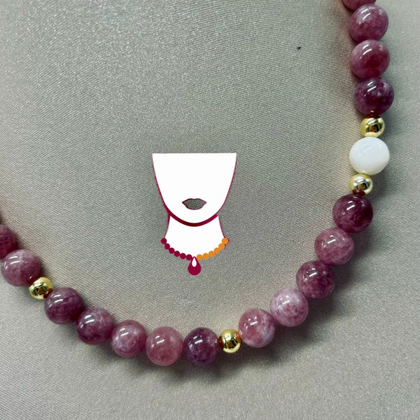 Necklace with purple beads and gold accents on a gray background