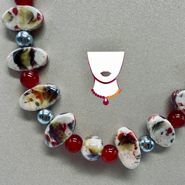 Necklace with marbled beads and red stones on a gray background