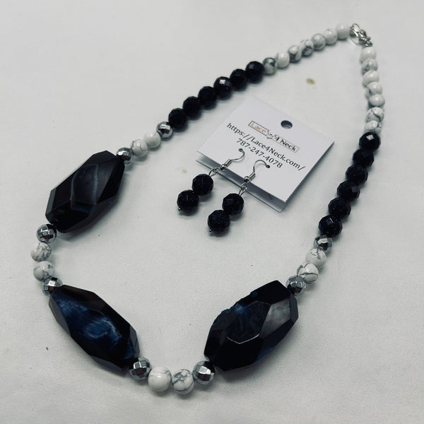 Necklace and earrings set with black and white beads on a white background