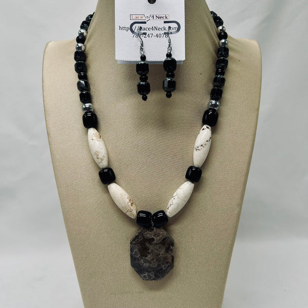 Black and white beaded necklace and earrings on a beige display with a visible brand tag.