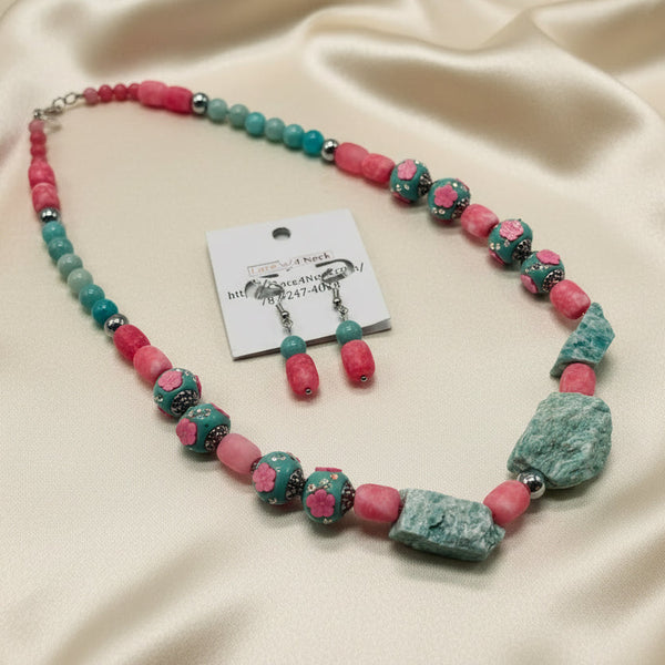 Necklace and earrings set with pink and green beads on a white background