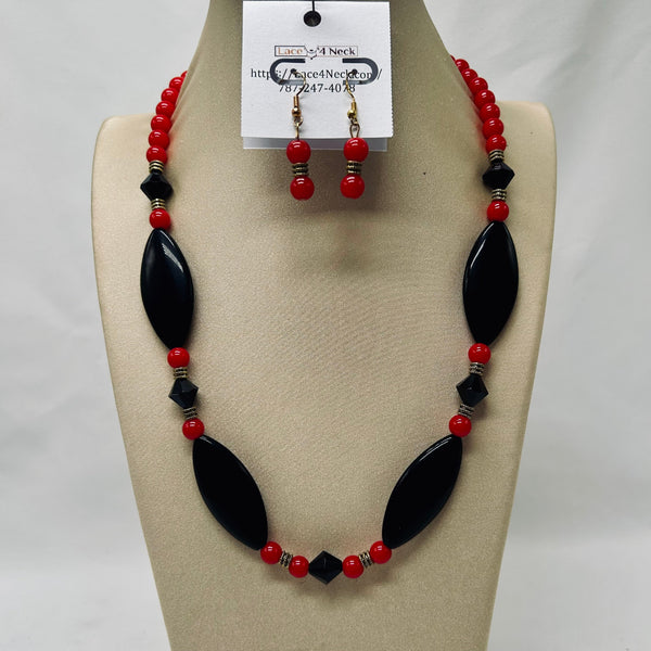 Necklace and earrings set with red and black beads on a beige display