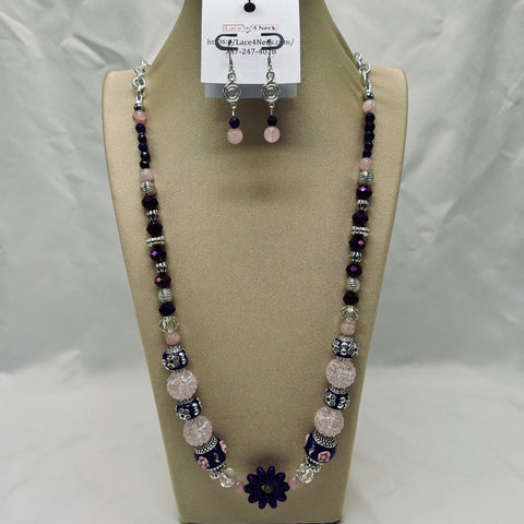 Beaded necklace and earrings set on a beige display with a white background
