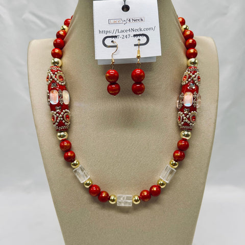 Red and gold beaded necklace and earrings on a mannequin bust with a visible brand tag.