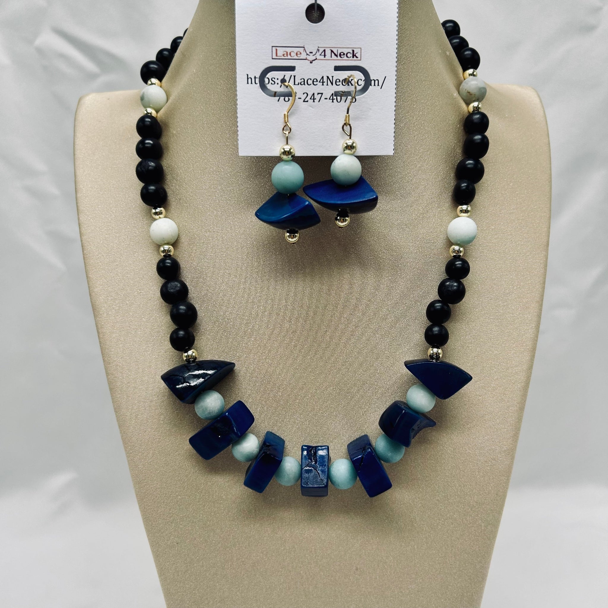 Necklace and earrings set on a mannequin bust with a visible brand tag.