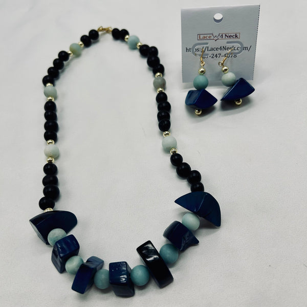 Necklace and earrings set with blue and black beads on a white background