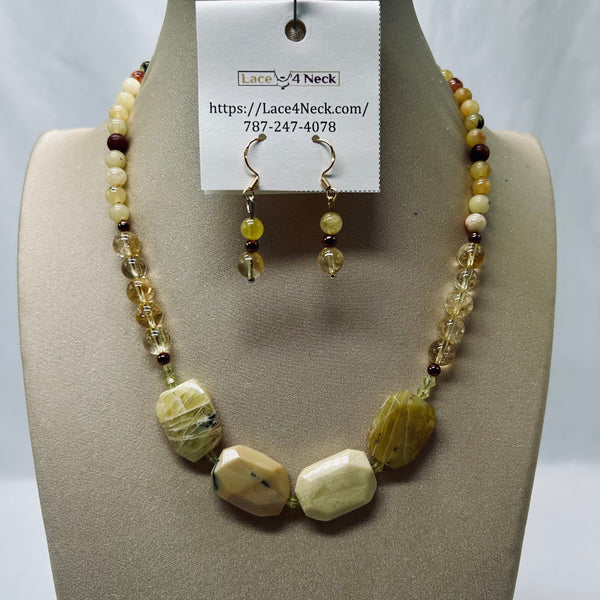 A beaded necklace and matching drop earrings displayed on a beige jewelry bust. The necklace features faceted pale yellow and cream beads, clear crystal beads, and a few dark brown accent beads, with three larger polished stone beads at the front.