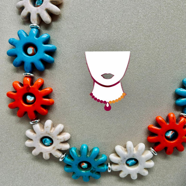Colorful necklace with blue, orange, and white floral-shaped beads on a gray background.