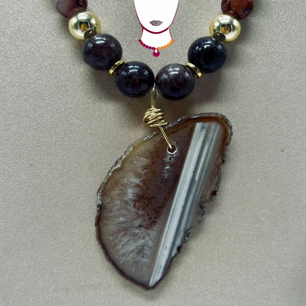 Necklace with dark beads and a large agate stone pendant on a neutral background