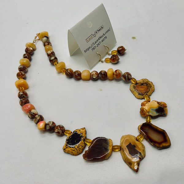 Necklace with brown and gold stones on a white surface, with a card in the background.