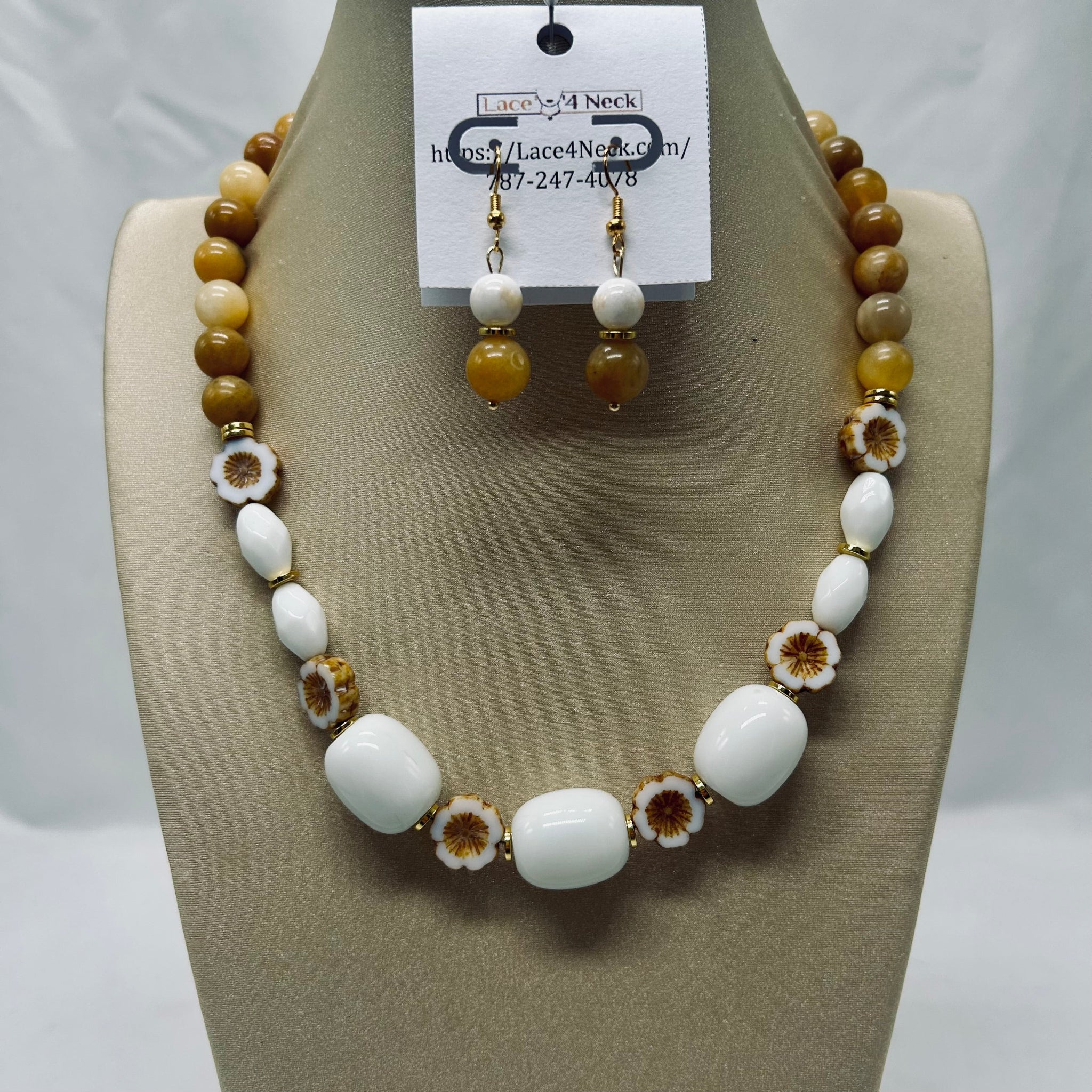 Necklace and earrings set on a mannequin bust with a visible brand tag.