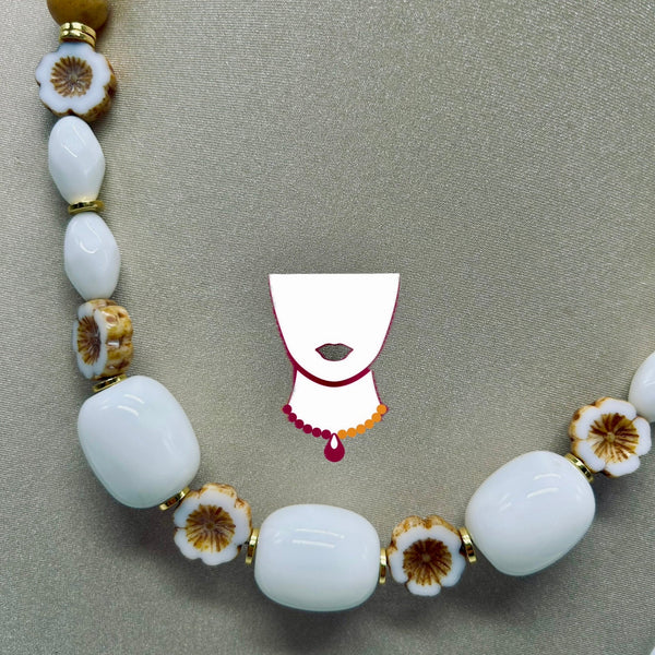 Necklace with white beads and floral elements on a gray background