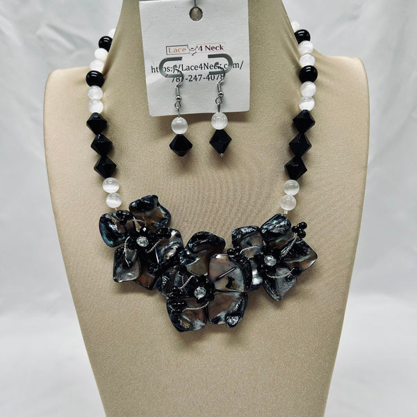 Necklace and earrings set on a beige display with a visible brand tag.