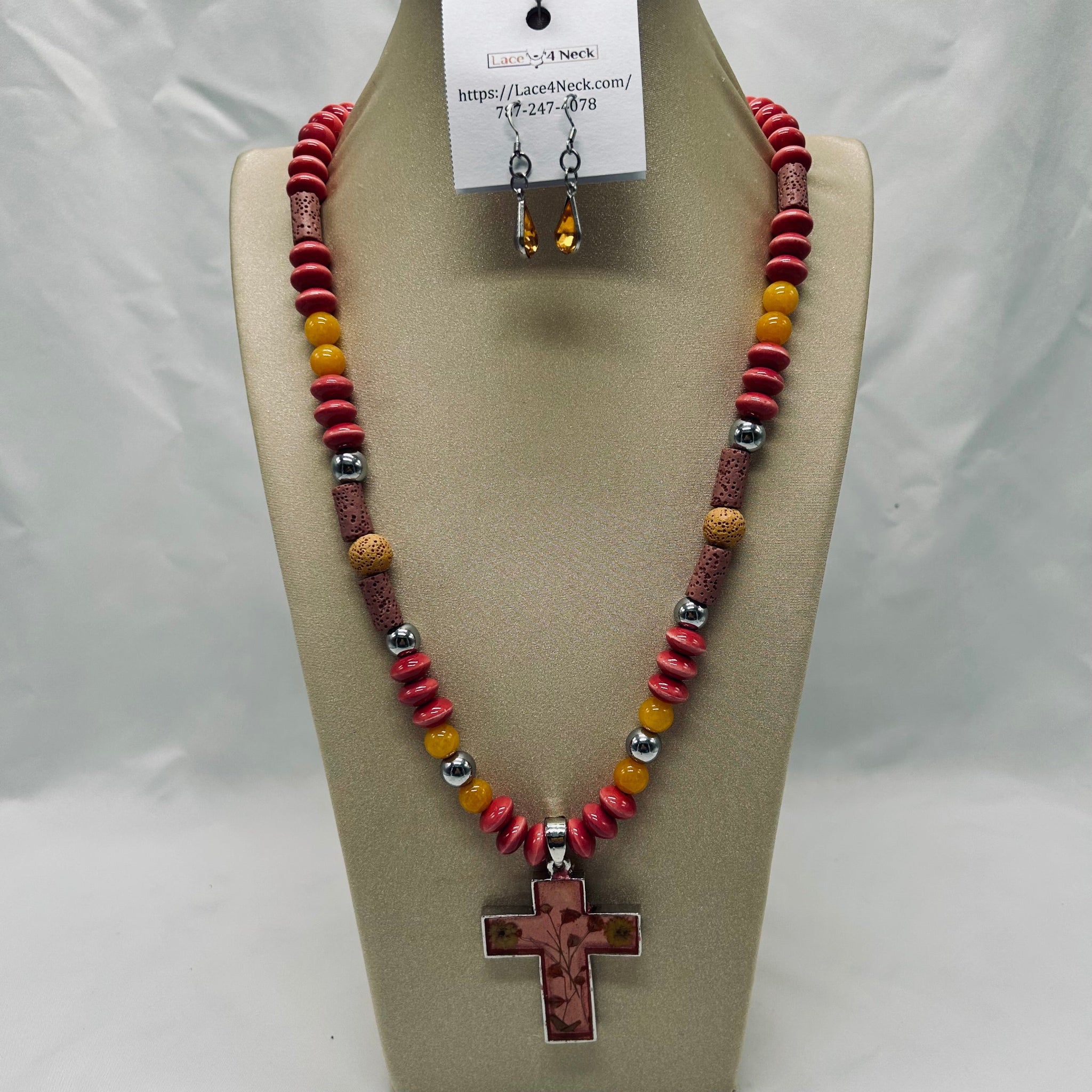 Necklace with cross pendant and beaded design on a beige display stand.
