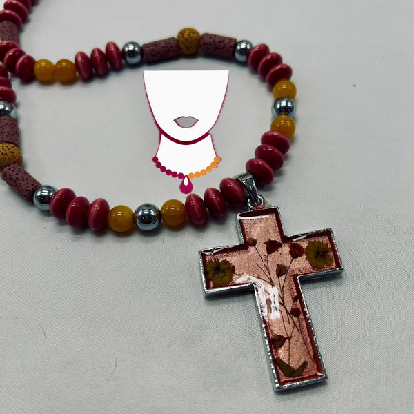 Beaded necklace with a cross pendant on a light gray background
