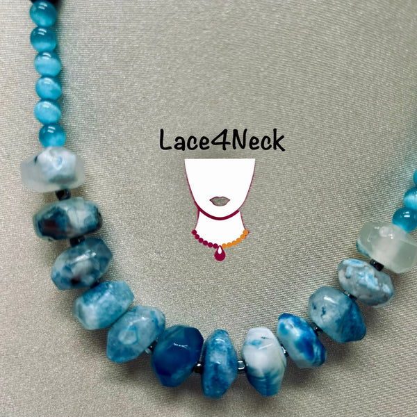 A beaded necklace with irregular blue and white marbled beads, displayed on a neutral gray textured background. The brand name 'Lace4Neck' is printed in the center with a stylized graphic of a neck wearing the necklace.