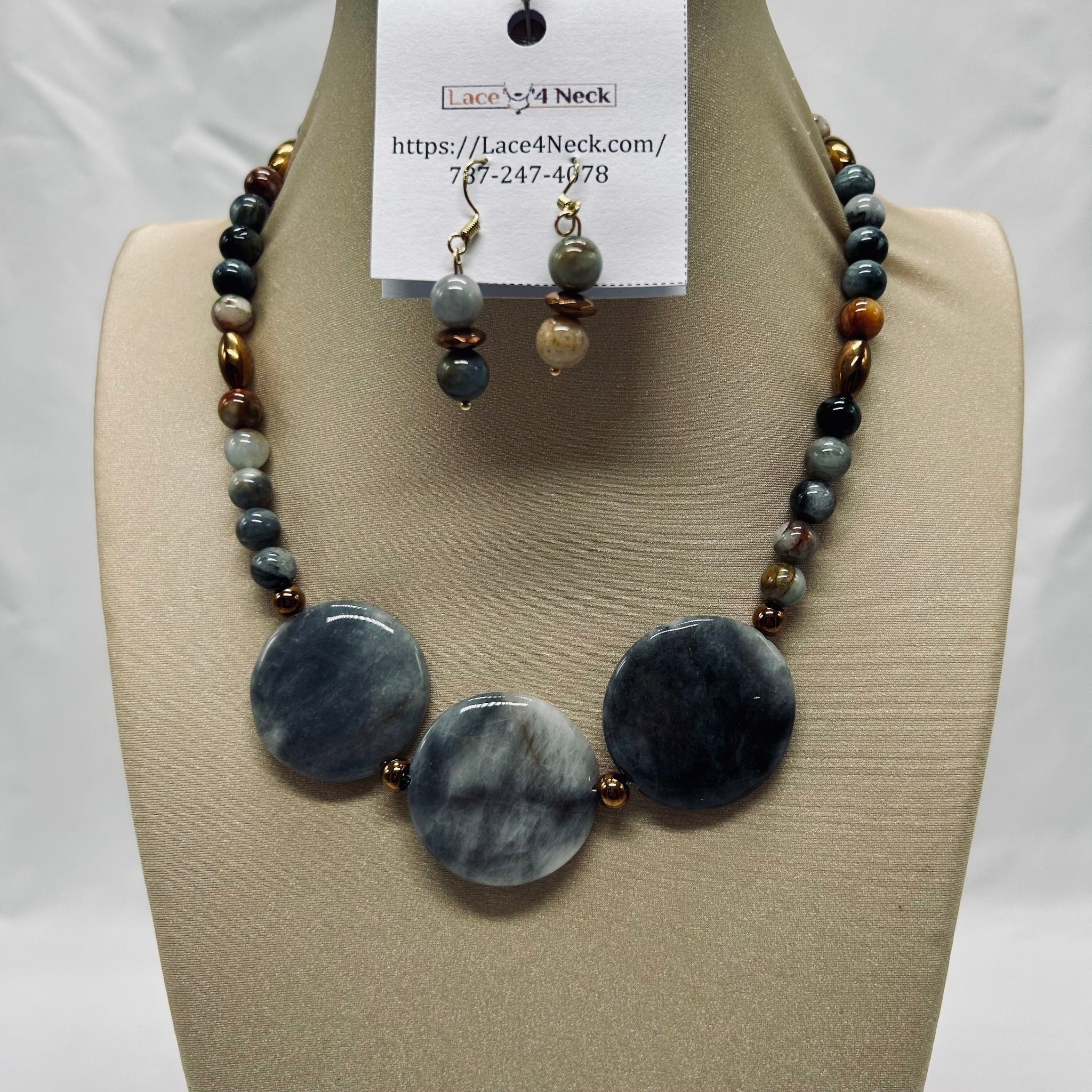 Necklace and earrings set on a mannequin bust with a visible brand label.
