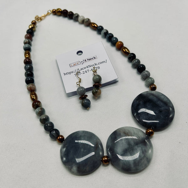 Necklace with large gray beads and smaller multicolored beads, accompanied by a matching earring set on a white background.