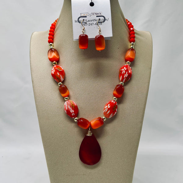 Necklace and earrings set with red and orange beads on a mannequin bust.