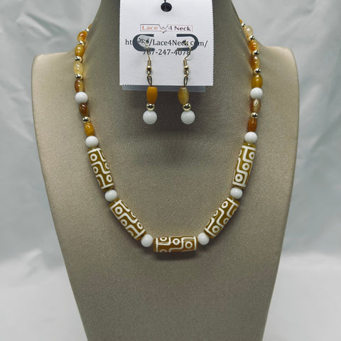 Beaded necklace and earrings set on a gray bust with a visible brand label.