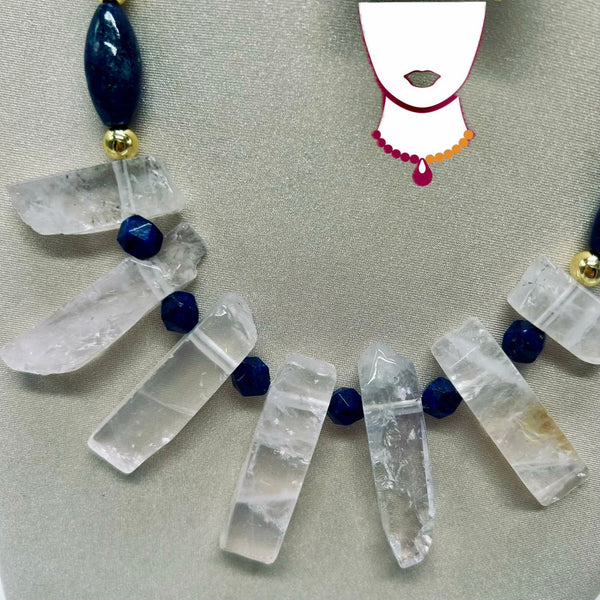 Crystal necklace with clear stones and blue beads on a neutral background
