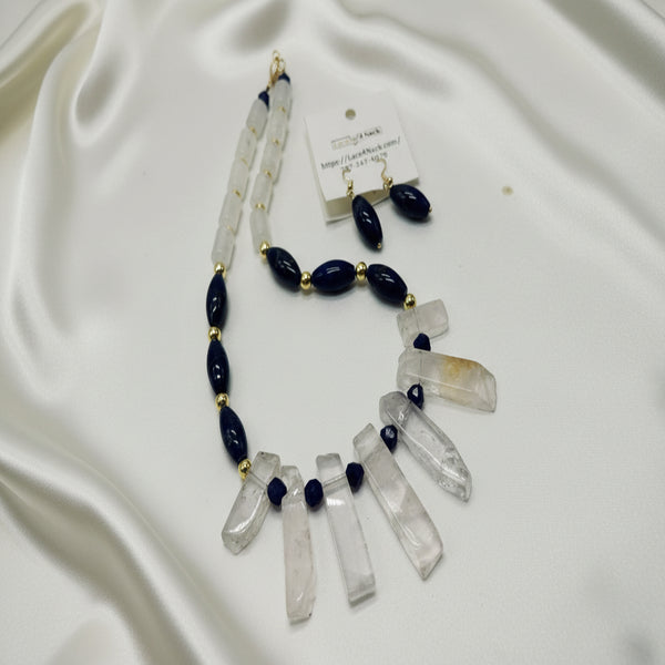 Necklace and earrings with dark beads and clear stone pendants on a white background