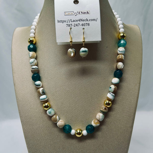 A beaded necklace and matching drop earrings displayed on a beige jewelry bust. The necklace features white beads, teal-blue beads, marbled beige and brown beads, and shiny gold spacer beads.