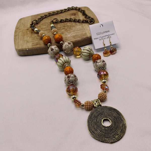 Necklace with large round pendant and beads on a wooden block with a card in the background