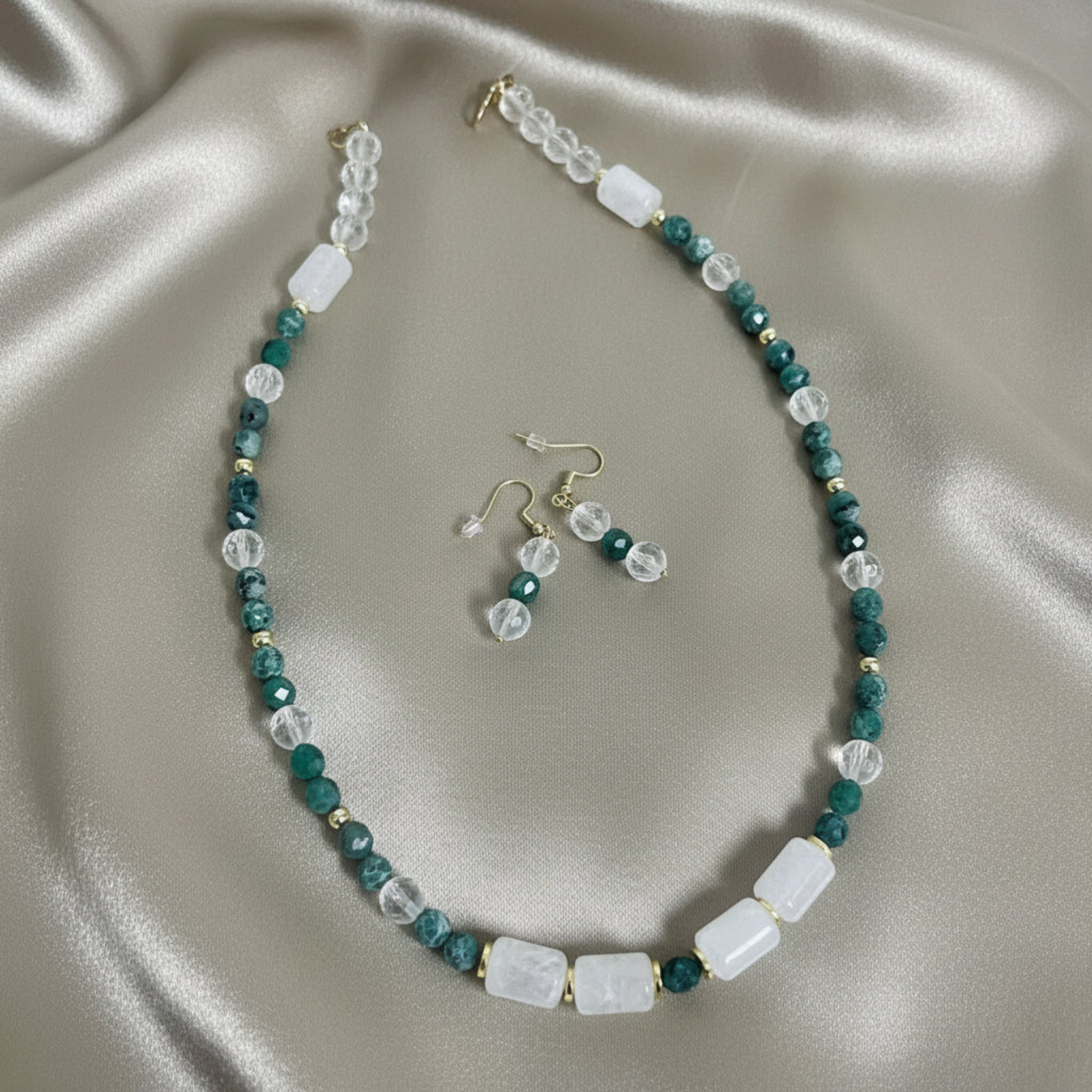 Beaded necklace and earrings set on a beige fabric background