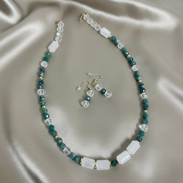 Beaded necklace and earrings set on a beige fabric background