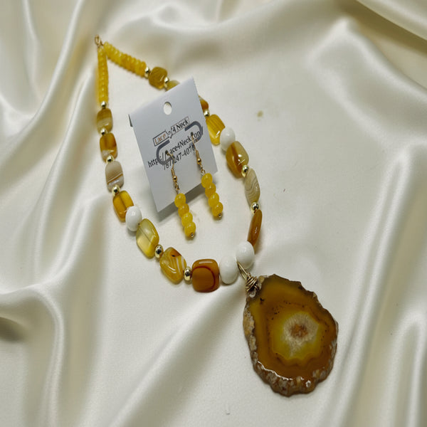 Necklace with agate slice pendant and matching earrings on a white background