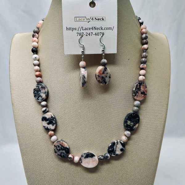 A beaded necklace and matching drop earrings displayed on a beige jewelry bust. The jewelry features marbled beads in black, white, pink, and gray, with a white hanging tag that reads Lace4Neck.