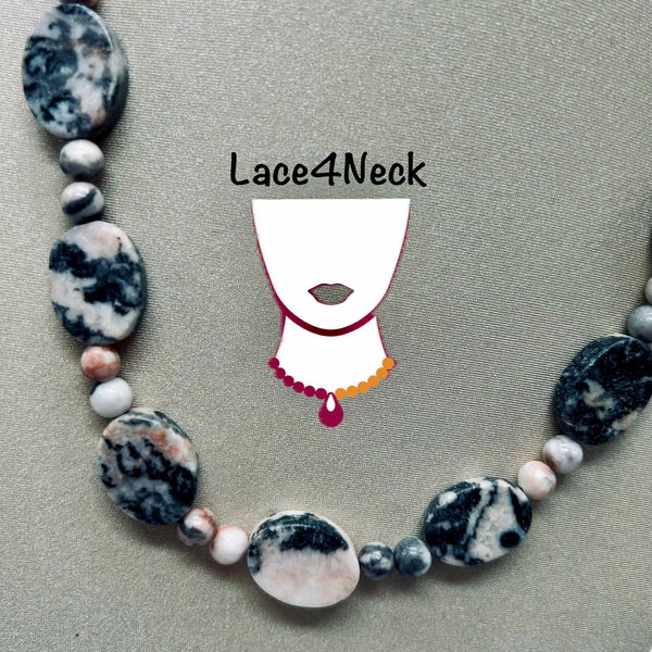 A beaded necklace with large oval stone beads, round gray beads, and smaller peach-colored beads, arranged in a circle on a textured beige background. A white stylized neck graphic with the text 'Lace4Neck' is overlaid in the center.