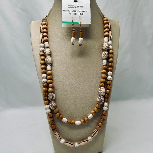 A multi-strand beaded necklace set displayed on a beige jewelry bust, including a long layered necklace and matching drop earrings. The beads are primarily natural brown wood, white ceramic, and cowrie shells, with some textured metallic silver beads.