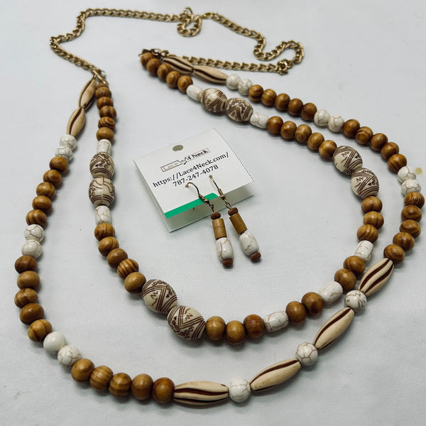 A beaded necklace and matching drop earrings displayed on a light gray background, with a small product tag card visible. The jewelry features round brown wooden beads, white marbled beads, and larger carved shell-like beads in brown and cream tones, with a gold-tone chain and gold-tone earring hooks.